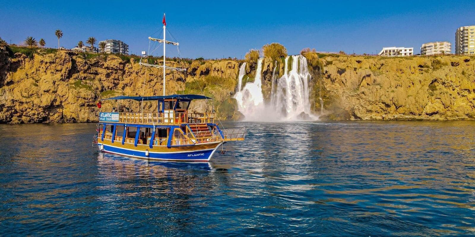 ანტალიაში, დუდენის ჩანჩქერების მახლობლად, ხის ნავის ხედი, კლდეებითა და მოწმენდილი ცის ფონზე.