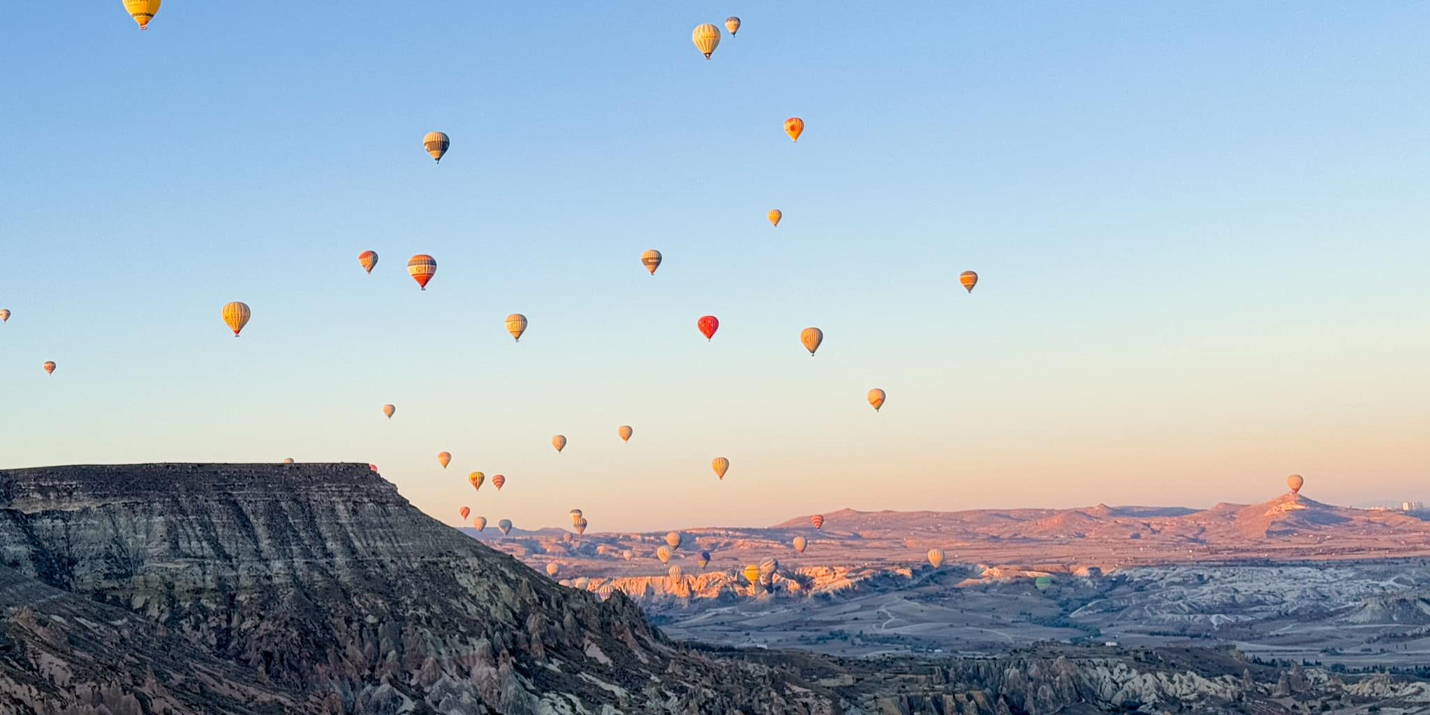 კაპადოკიის ფოტპ მზის ჩასვლისას, კლდისა და საჰაერო ბუშტების ფონზე