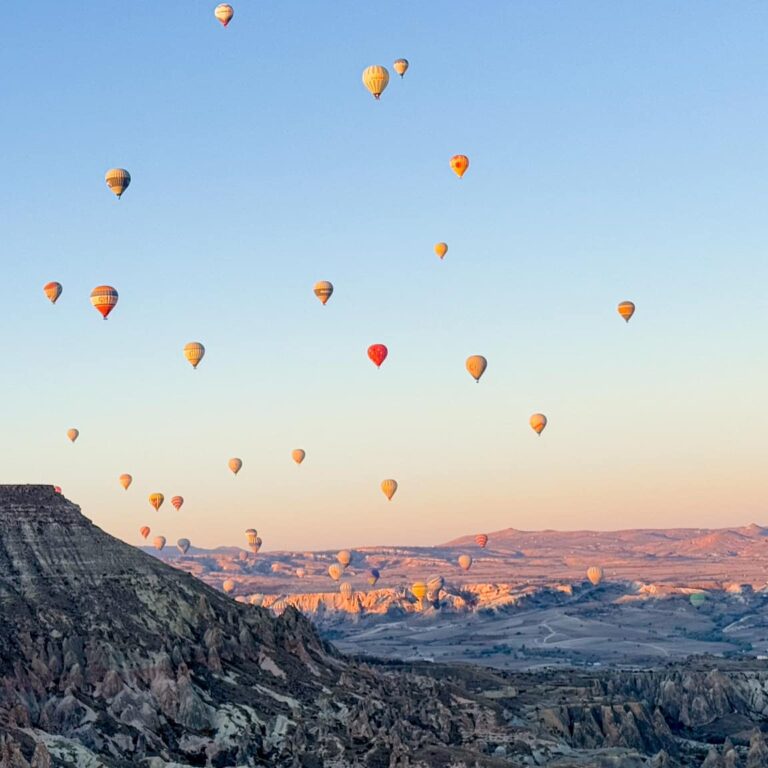 კაპადოკიის ფოტპ მზის ჩასვლისას, კლდისა და საჰაერო ბუშტების ფონზე