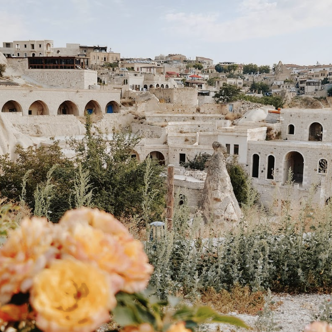 კაპადოკია, თურქეთი. ძველი კლდოვანი სახლები, წინა პლანზე ყვითელი ყვავილით