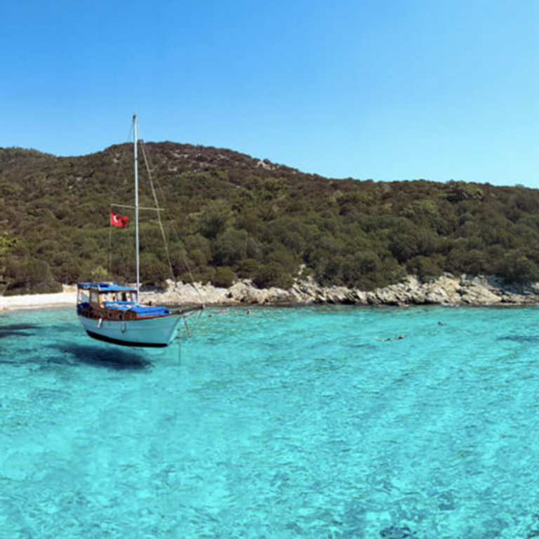 ალანიის სანაპირო, თურქეთი. ფირუზისფერ სუფთა წყალში პატარა იახტა.